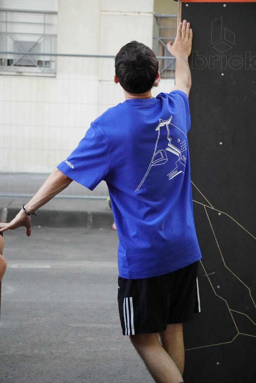 Enzo Chupin de dos, main posée sur un mur, en pleine session de parkour